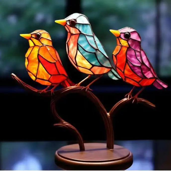 Colorful stained glass birds on a branch against a blurred natural background
