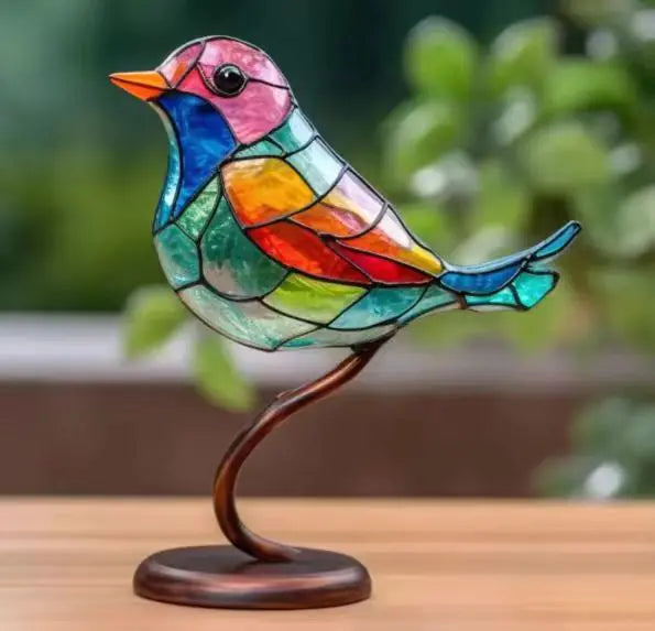 Colorful stained glass bird sculpture on a wooden surface with a blurred green background