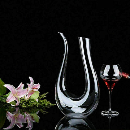Clear glass wine decanter with a glass of red wine on a black background