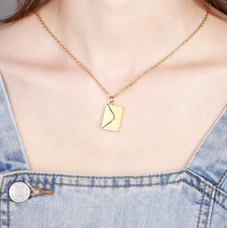 Gold necklace with a unique pendant worn by a person in a denim outfit.