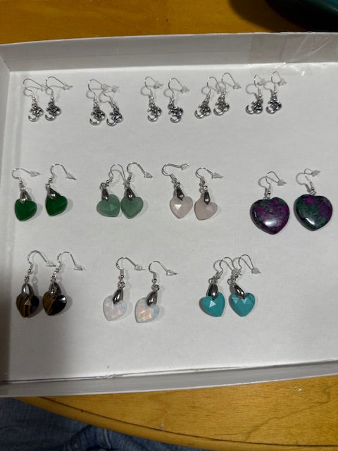 Assorted earrings displayed on a card with a wooden surface in the background