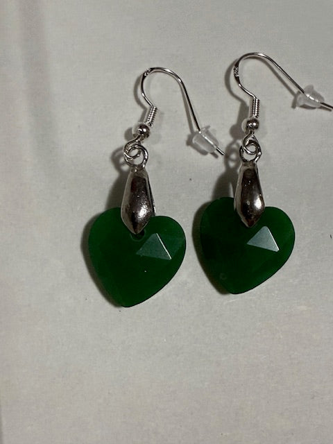 Green heart-shaped earrings with silver hooks on a light gray background