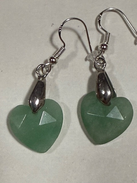 Green heart-shaped earrings with silver hooks on a light background