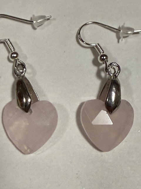 Heart-shaped earrings with pink stones on a light gray background