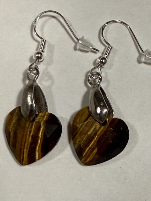 Heart-shaped tigers eye stone earrings with silver hooks on a light gray background