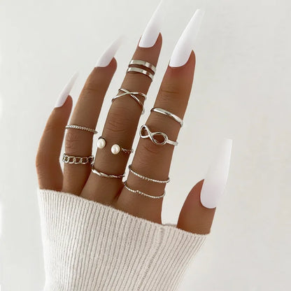 Hand wearing multiple silver rings with a plain background