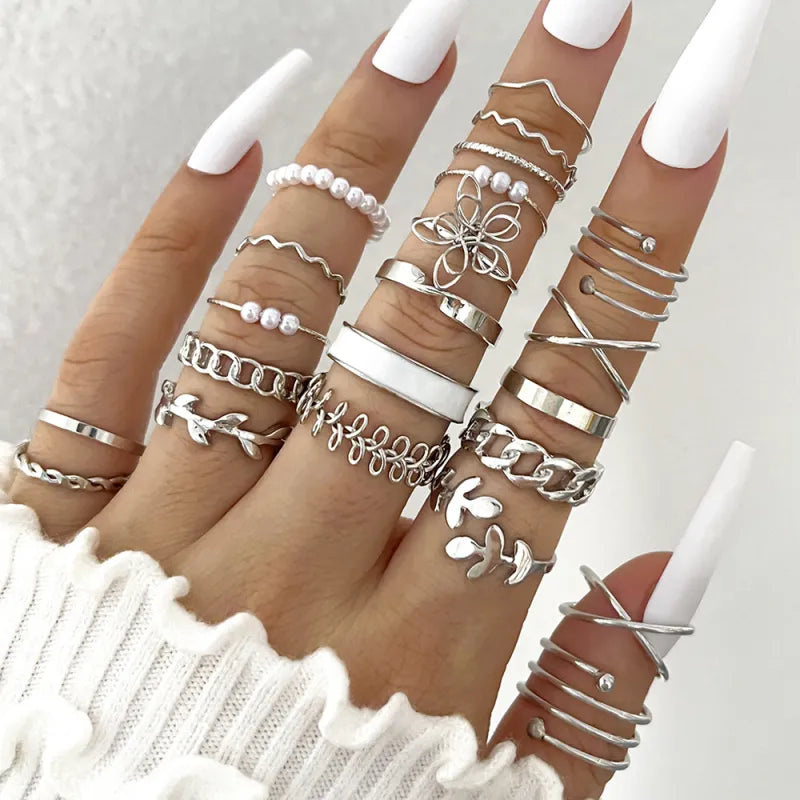 Multiple silver rings on fingers with a white background