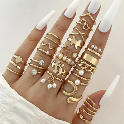 Multiple gold rings with various designs on a hand against a neutral background