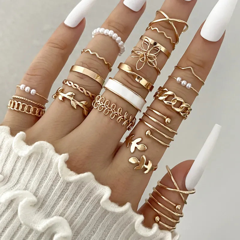 Close-up of fingers wearing multiple gold rings on a neutral background