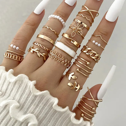 Close-up of fingers wearing multiple gold rings on a neutral background