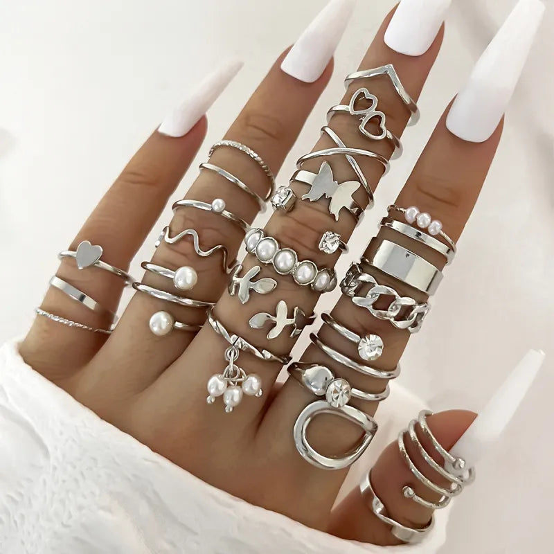 Hand wearing multiple silver rings with various designs on a white background