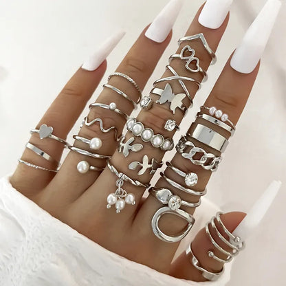 Hand wearing multiple silver rings with various designs on a white background