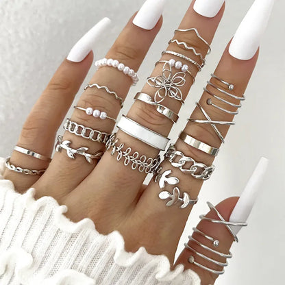 Multiple silver rings on fingers with a white background