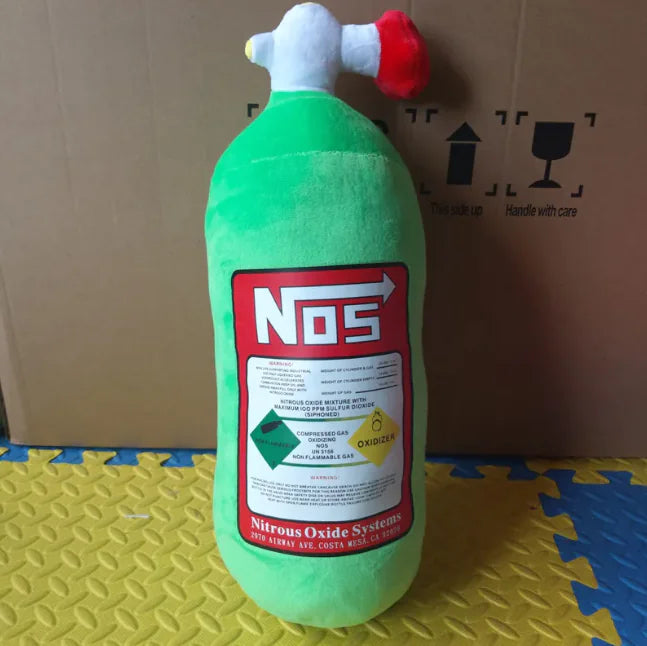 Green plush toy resembling a NO2 can with a red label on a yellow and blue mat.