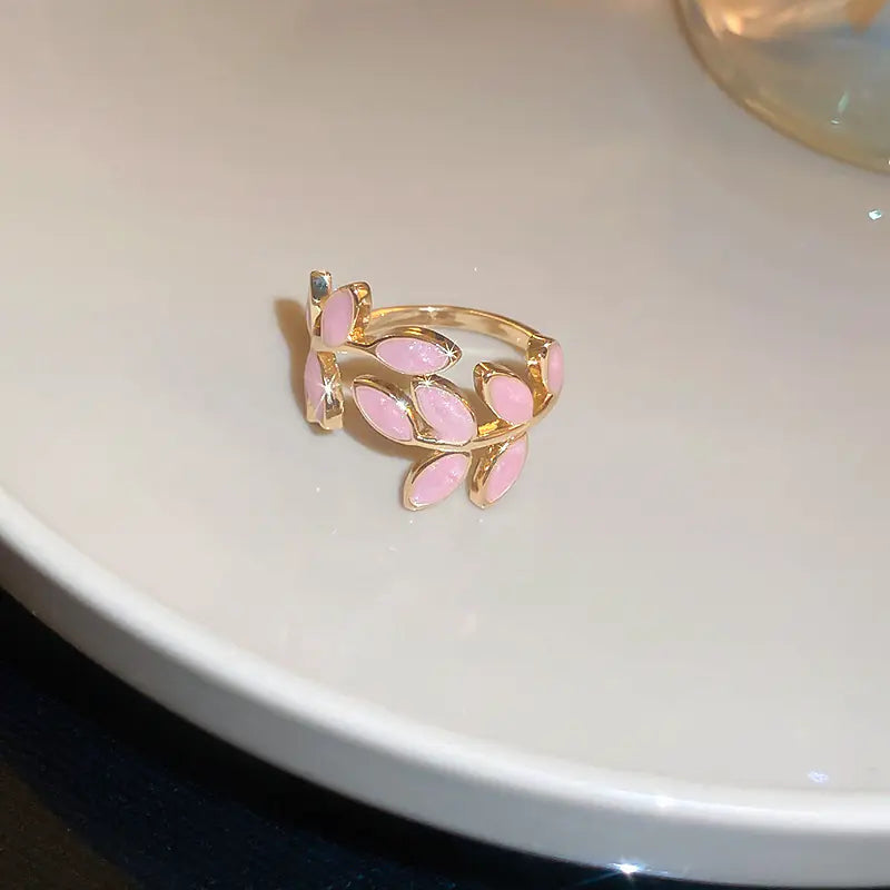 Gold ring with pink leaves on a white surface