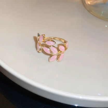 Gold ring with pink leaves on a white surface