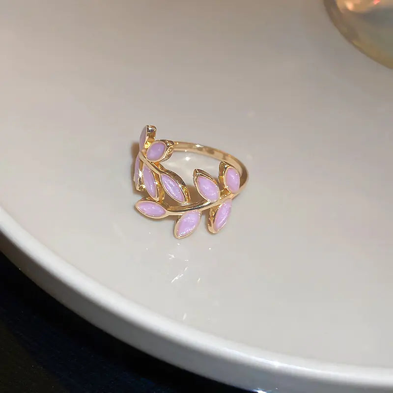 Gold ring with pink stones on a white surface