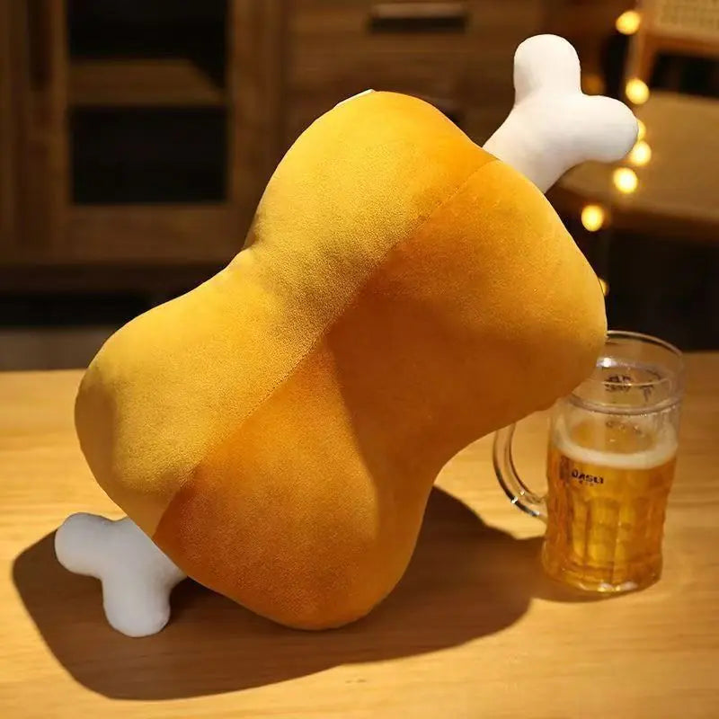 Plush toy shaped like a chicken leg on a table with a glass of beer.