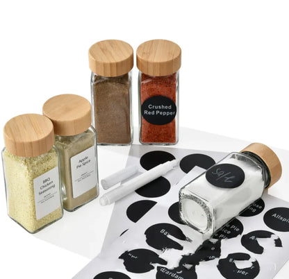Set of spice jars with wooden lids on a white surface with black labels.